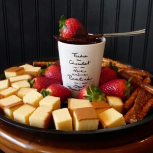 A tray of delicious chocolate fondue with strawberries, cake, and pretzels, offering a tempting dessert option.